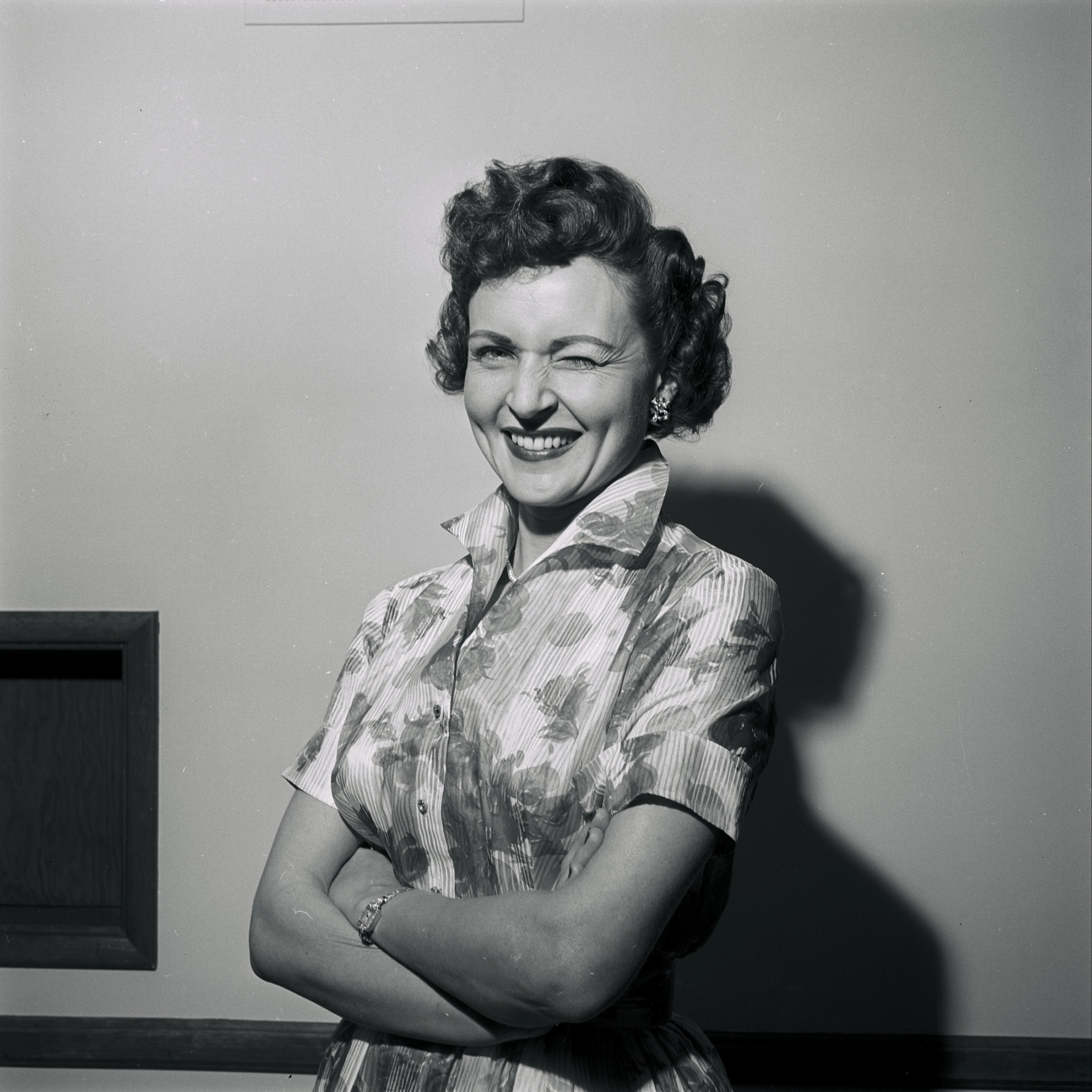 Betty winking with arms folded