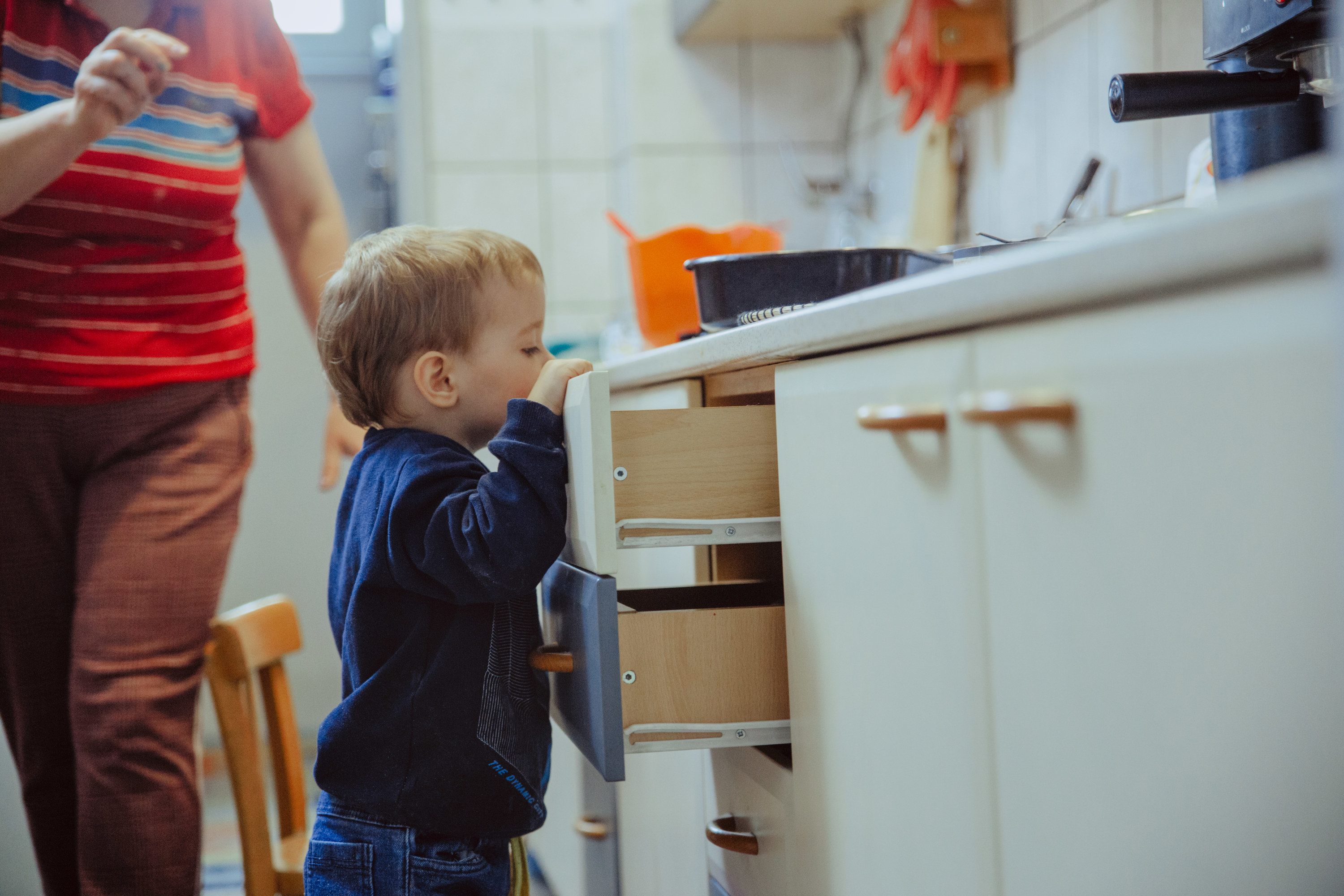 little boy peering into a drawer as an adult moves to stop him
