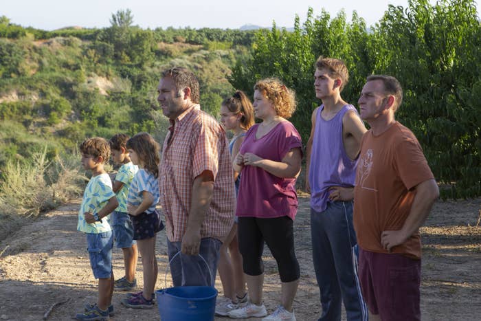 A family stands in an orchard together