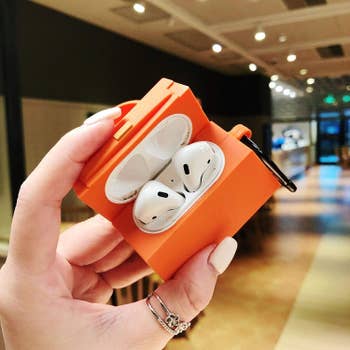 The orange case, opened to show the airpods inside