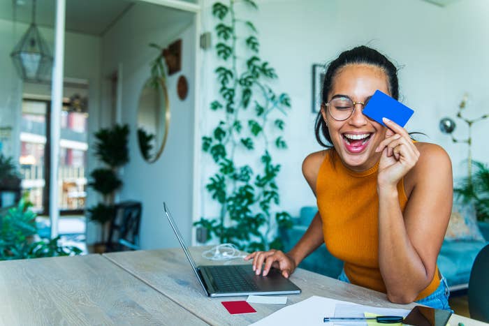 young woman holding a credit card in front of a laptop for online shopping