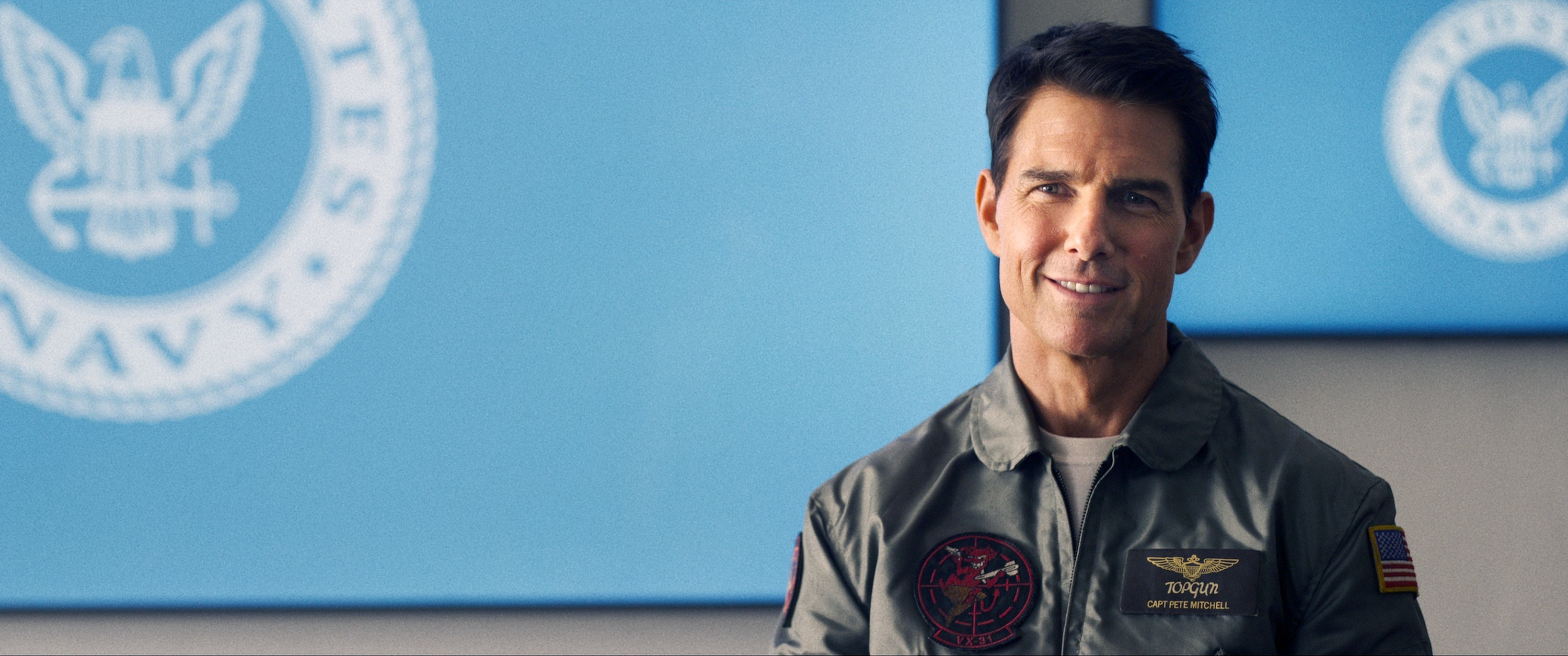 Tom Cruise stands in front of a screen