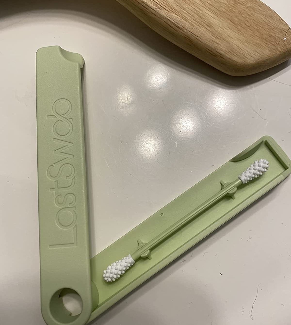 a reviewer photo of the reusable swab in a green case that reads &quot;LastSwab&quot;