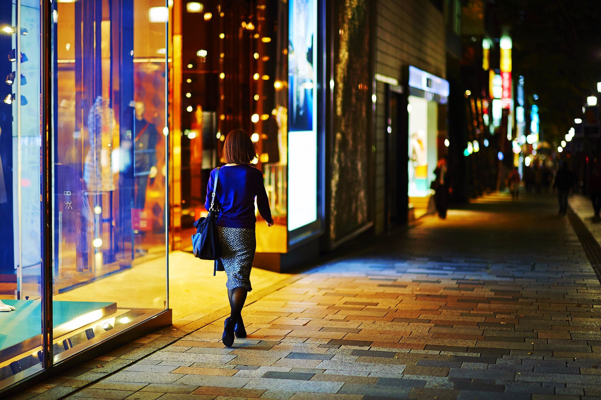 A woman walking along a city street at night
