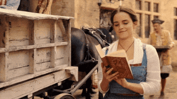 Emma Watson reading a book while walking.