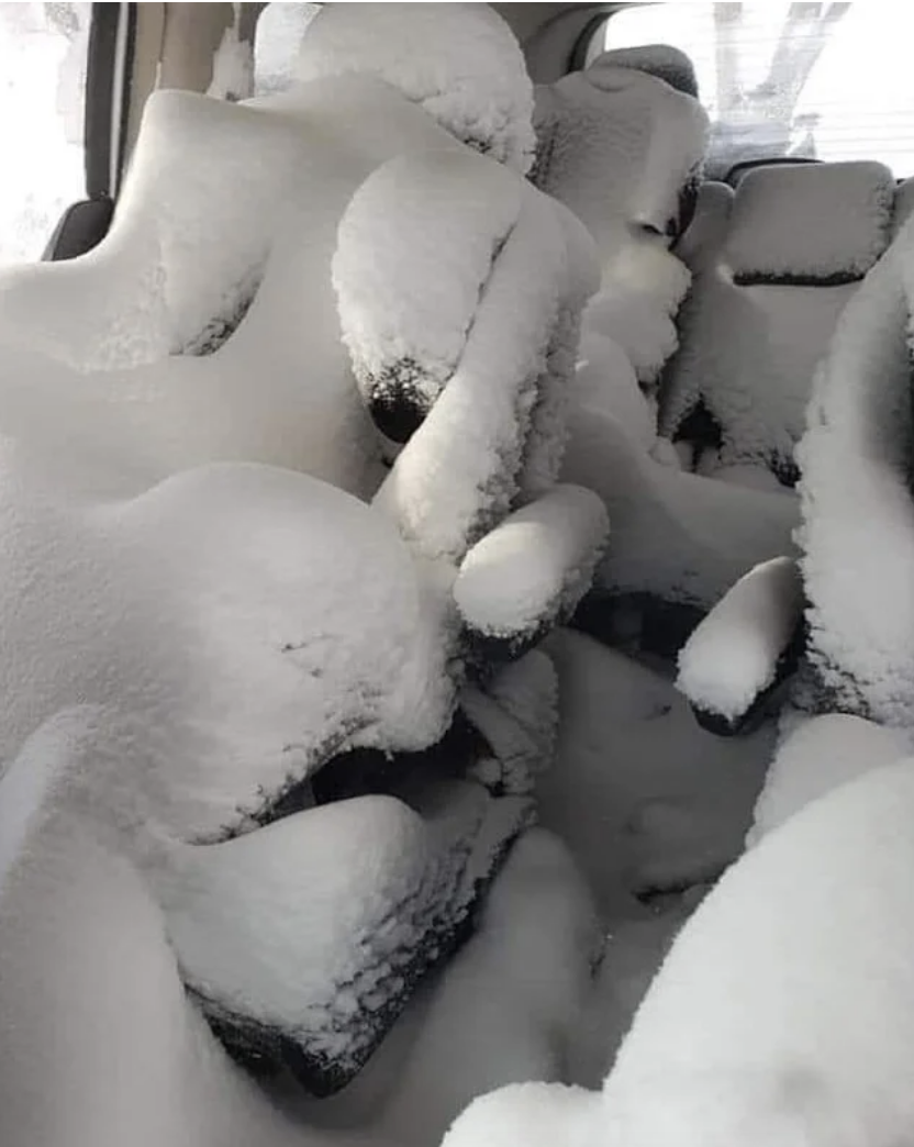 A car interior with snowdrifts covering every seat