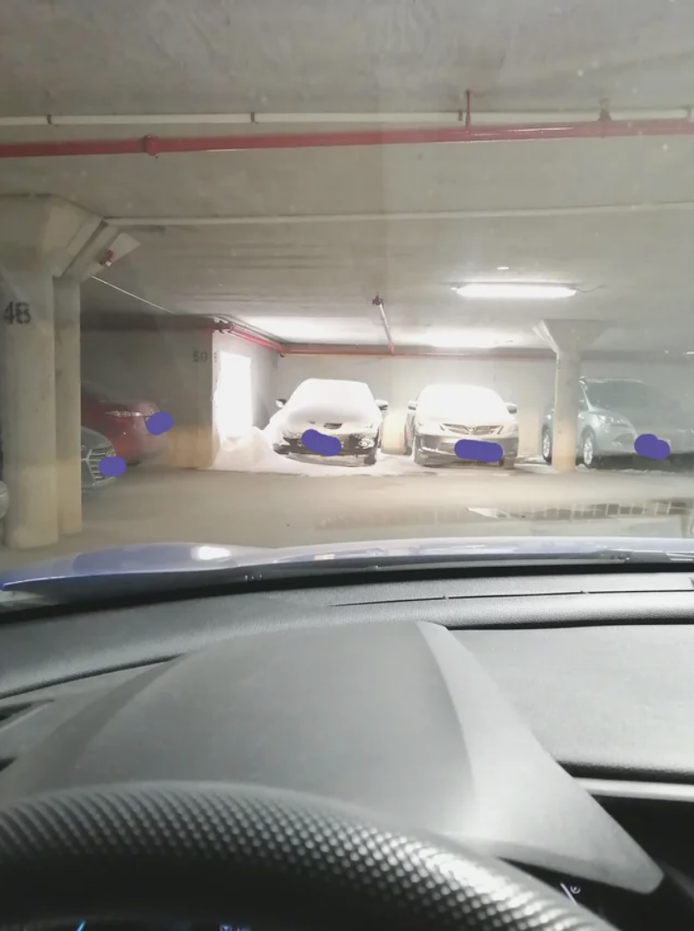 Two cars in a parking garage with snow on them