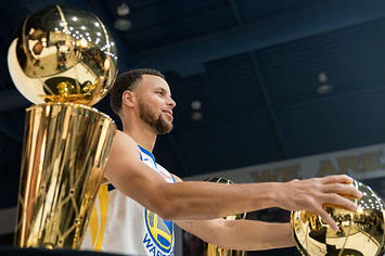 Stephen Curry poses with the Warriors' Larry O'Brien trophies.
