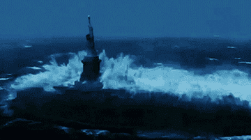 A massive wave crashes around the Statue of Liberty