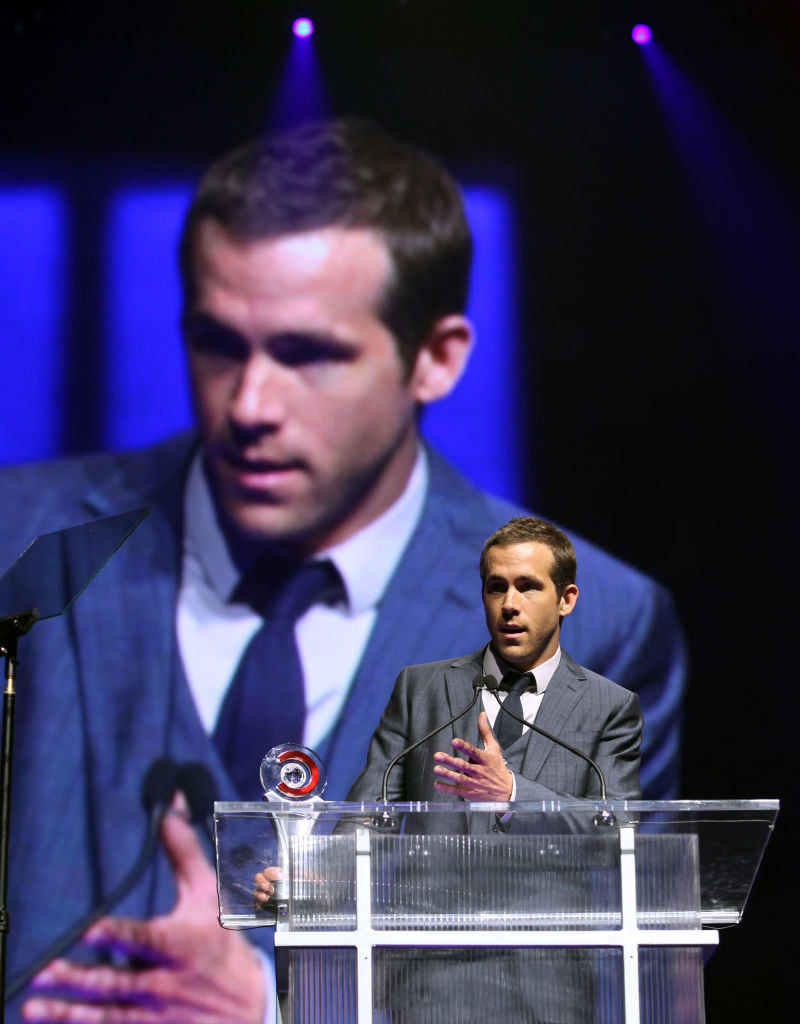 Ryan at a podium with an award with a large image of himself behind him
