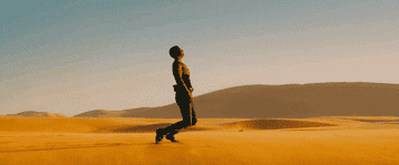 Charlize Theron collapses to her knees in the desert
