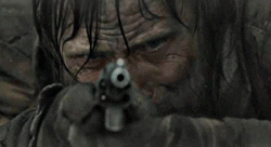 Viggo Mortensen aims a gun at the camera in The Road
