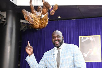 Shaq points at a statue of him dunking.