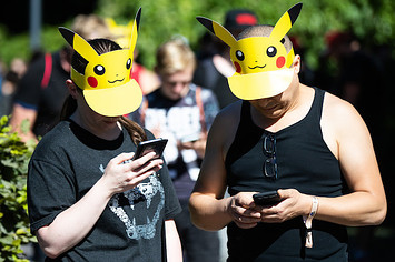 Two participants with Pokemon sun vizors playing 'Pokemon Go' on their mobile phones.