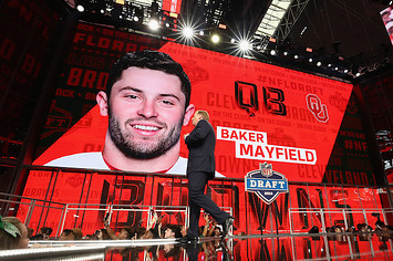 Roger Goodell walks past a video board displaying an image of Baker Mayfield.