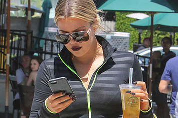 Khloe Kardashian looks at her phone.