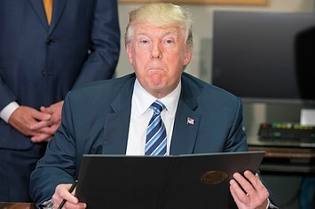 Donald J. Trump looks over the first of three Executive Orders concerning financial services