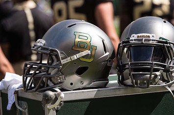 Two Baylor football helmets sitting on the sidelines.