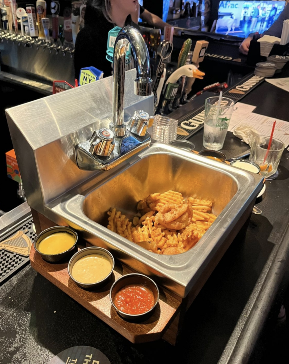An order of fries is served inside an actual sink that has been pulled out and is now being used like a tray
