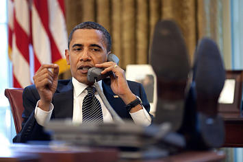 Obama talks on the phone at his desk.