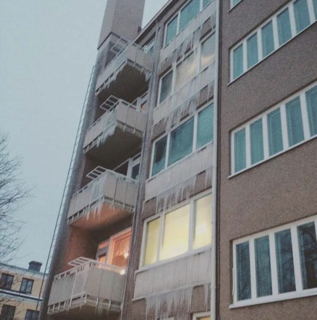 An apartment building exterior with icicles hanging from every window and balcony