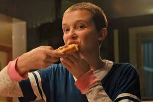 Eleven from Stranger Things eating a slice of pizza