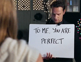 a gif of a person holding a sign that says &quot;to me, you are perfect&quot; from Love Actually