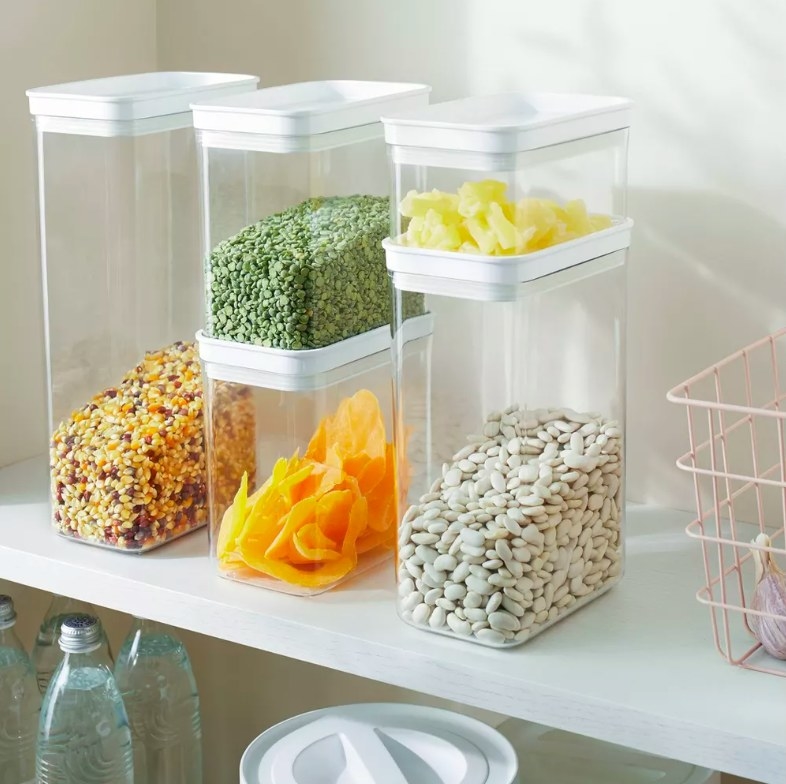 Clear storage containers filled with food on pantry shelves