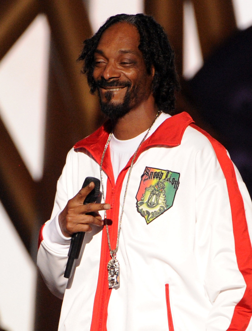 Snoop smiling with a mic onstage