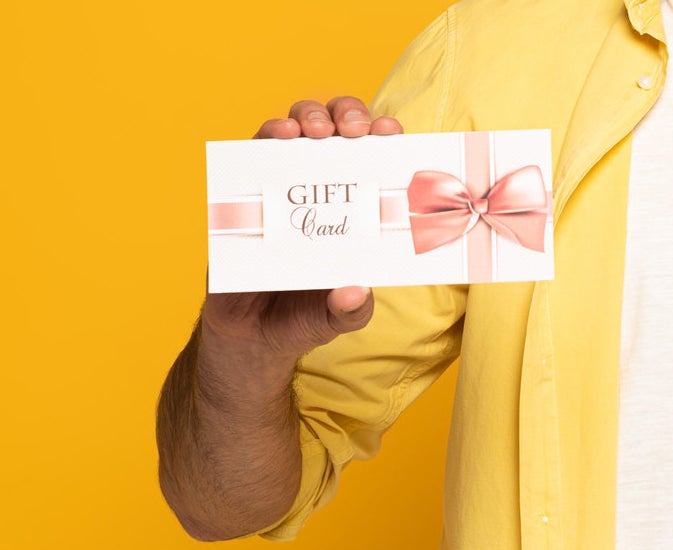 A person holding a gift card with a bow on it