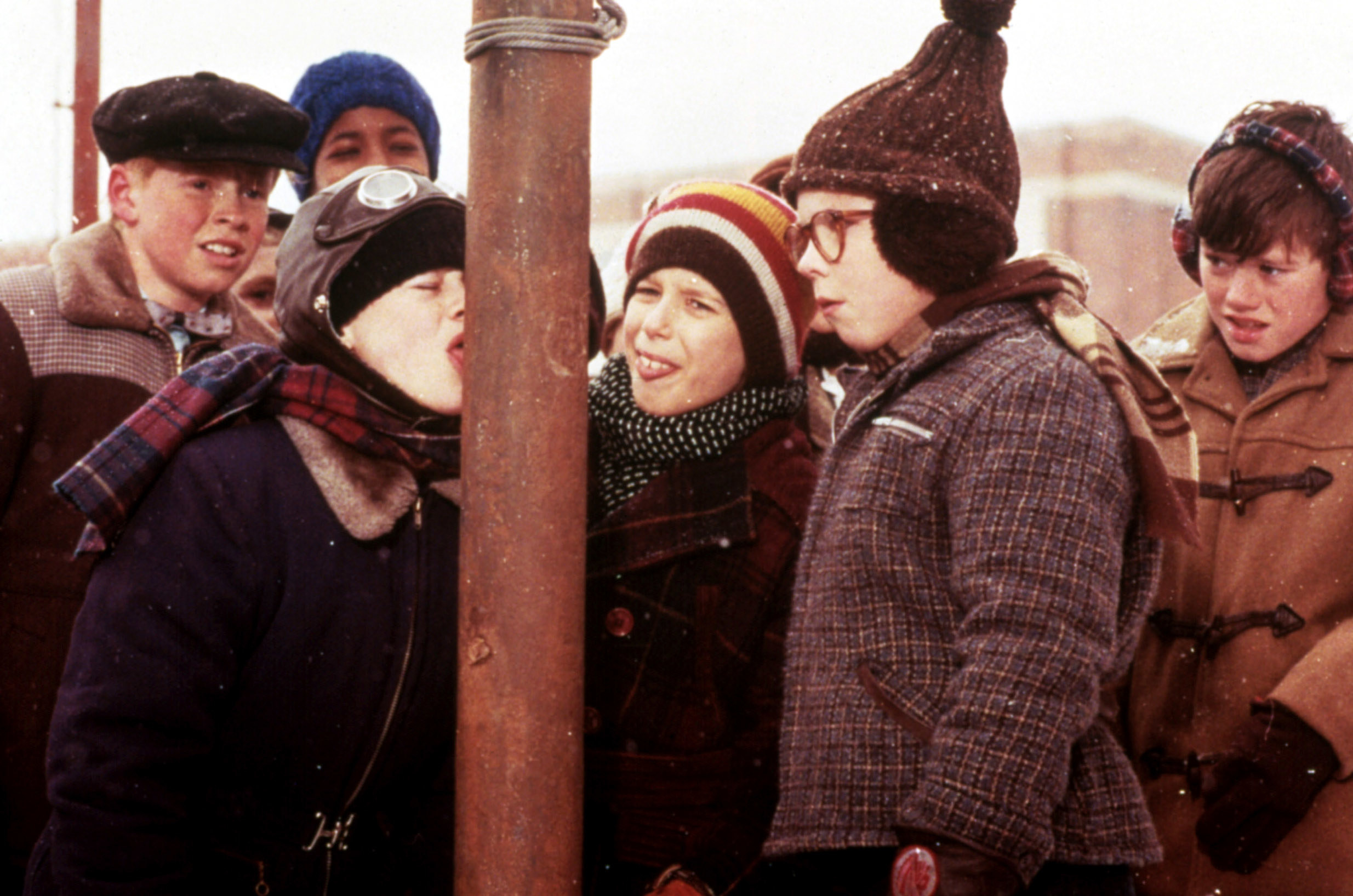 kids looking as one kid&#x27;s tongue is stuck to a pole