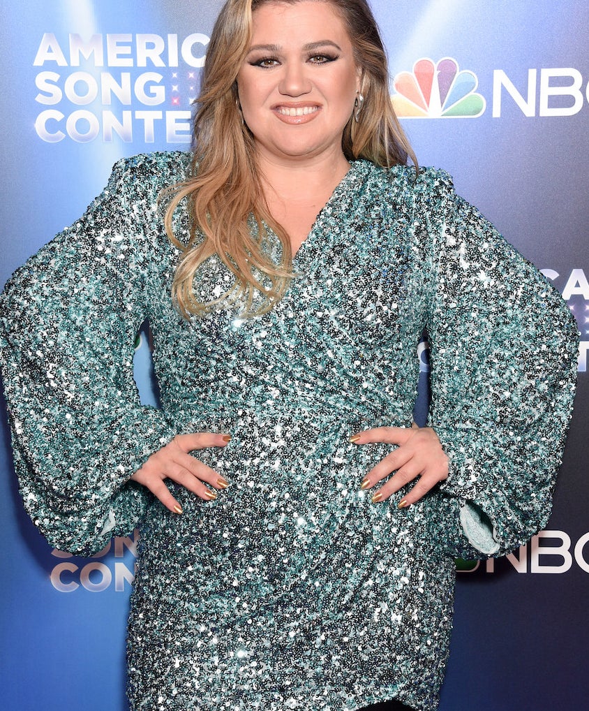 Kelly Clarkson smiling with her hands on her hips