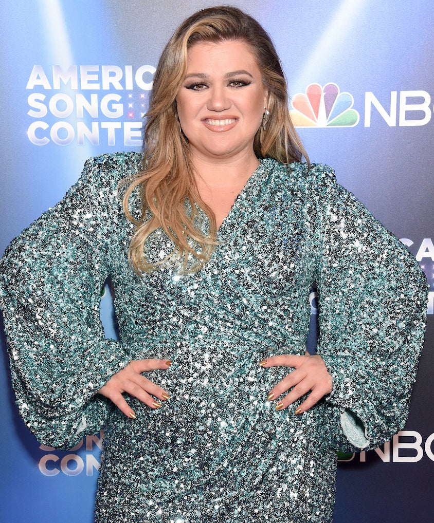 Kelly Clarkson smiling with her hands on her hips