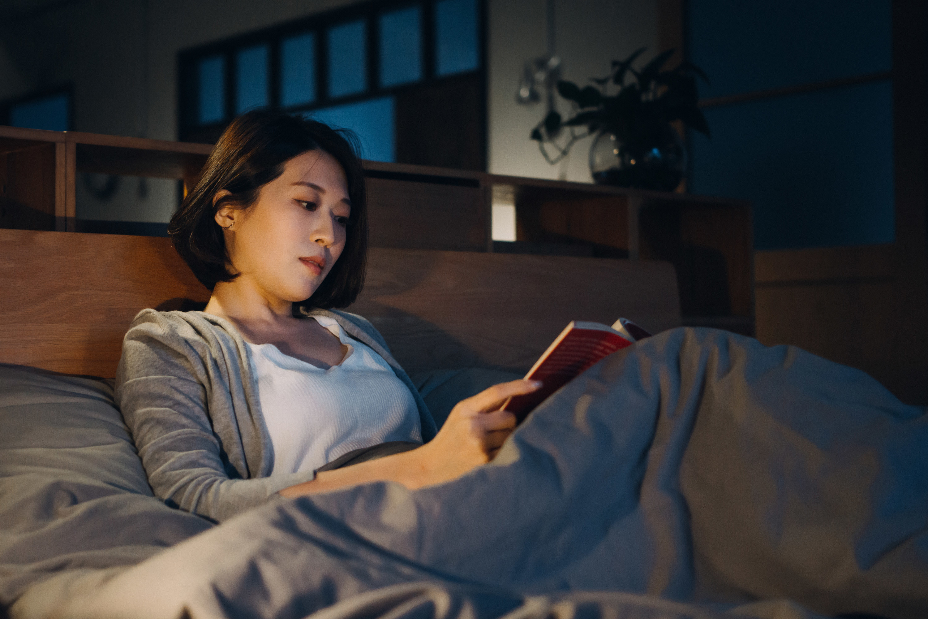 a woman reading a book in her bed at night