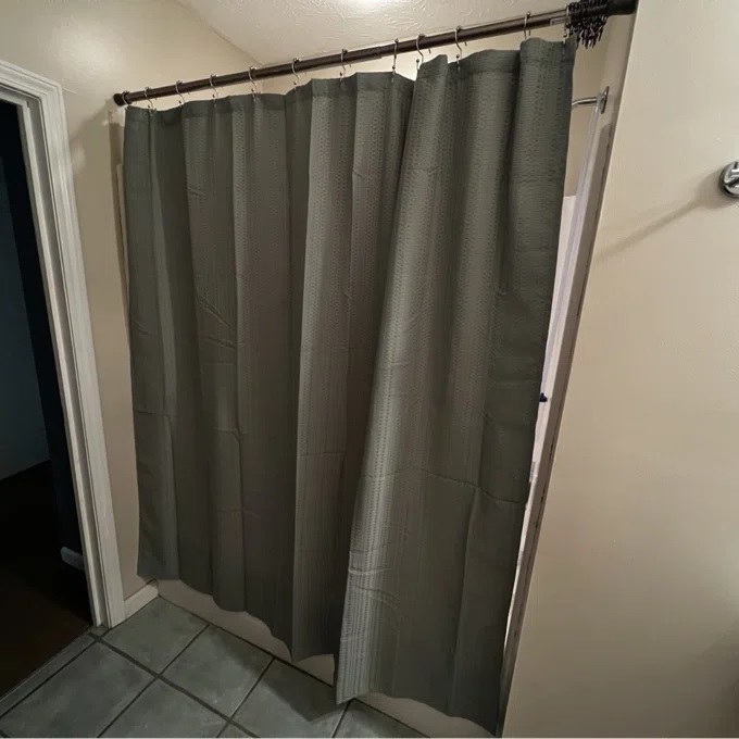 The buyers shower curtain hung in the sage green color