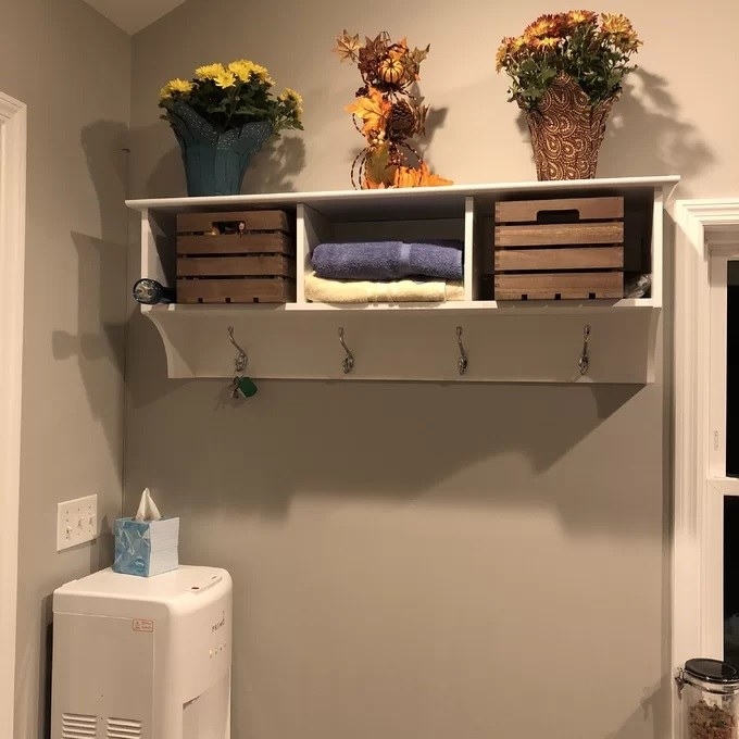 The mounted coat rack with two storage baskets and plants on top