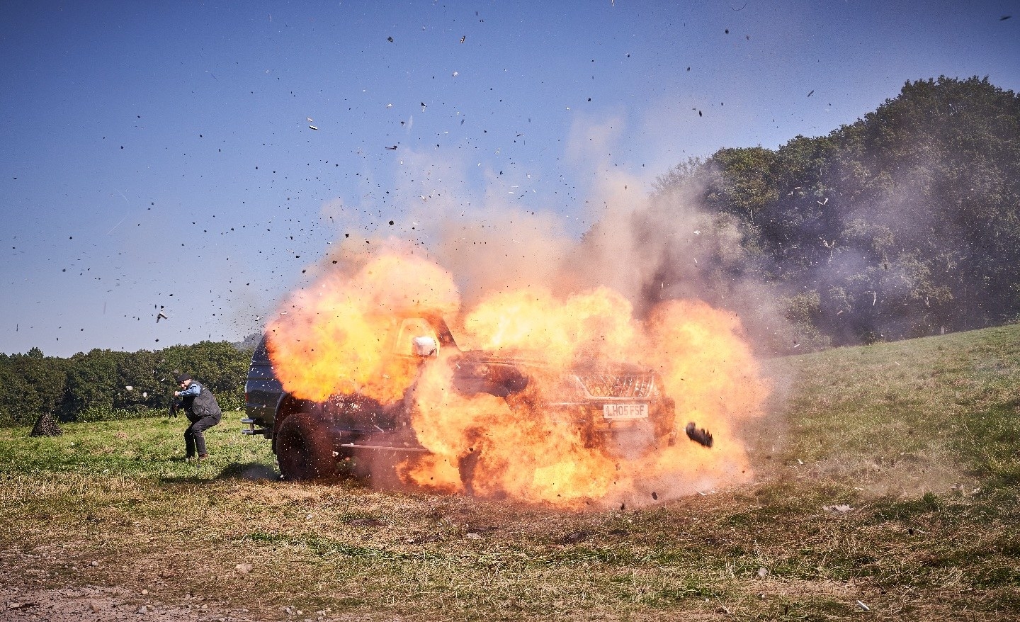 A car explodes after being attacked by mercenaries on a helicopter