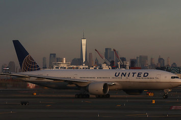 United Airlines airplane passes the skyline of lower Manhattan and One World Trade Center.