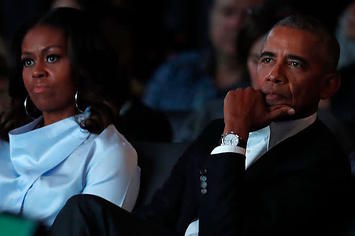 Michelle and Barack Obama listening to remarks at the Obama Foundation Summit.