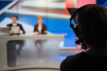 Cameraman filming news in television studio.