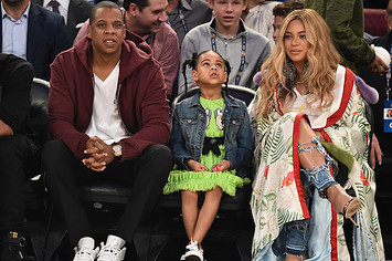 This is Jay Z, Beyoncé, and Blue Ivy at a basketball game.