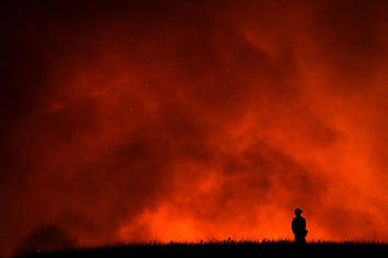 A firefighter watches as a California wildfire rages.