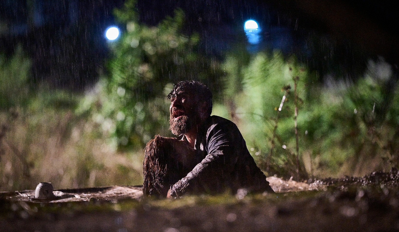 A crying and muddy man attempts to retrieve his wife from a living burial