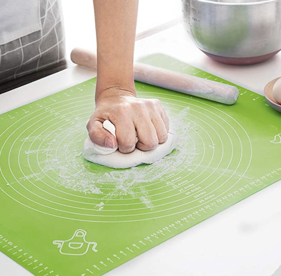 a person kneading dough on the silicone mat