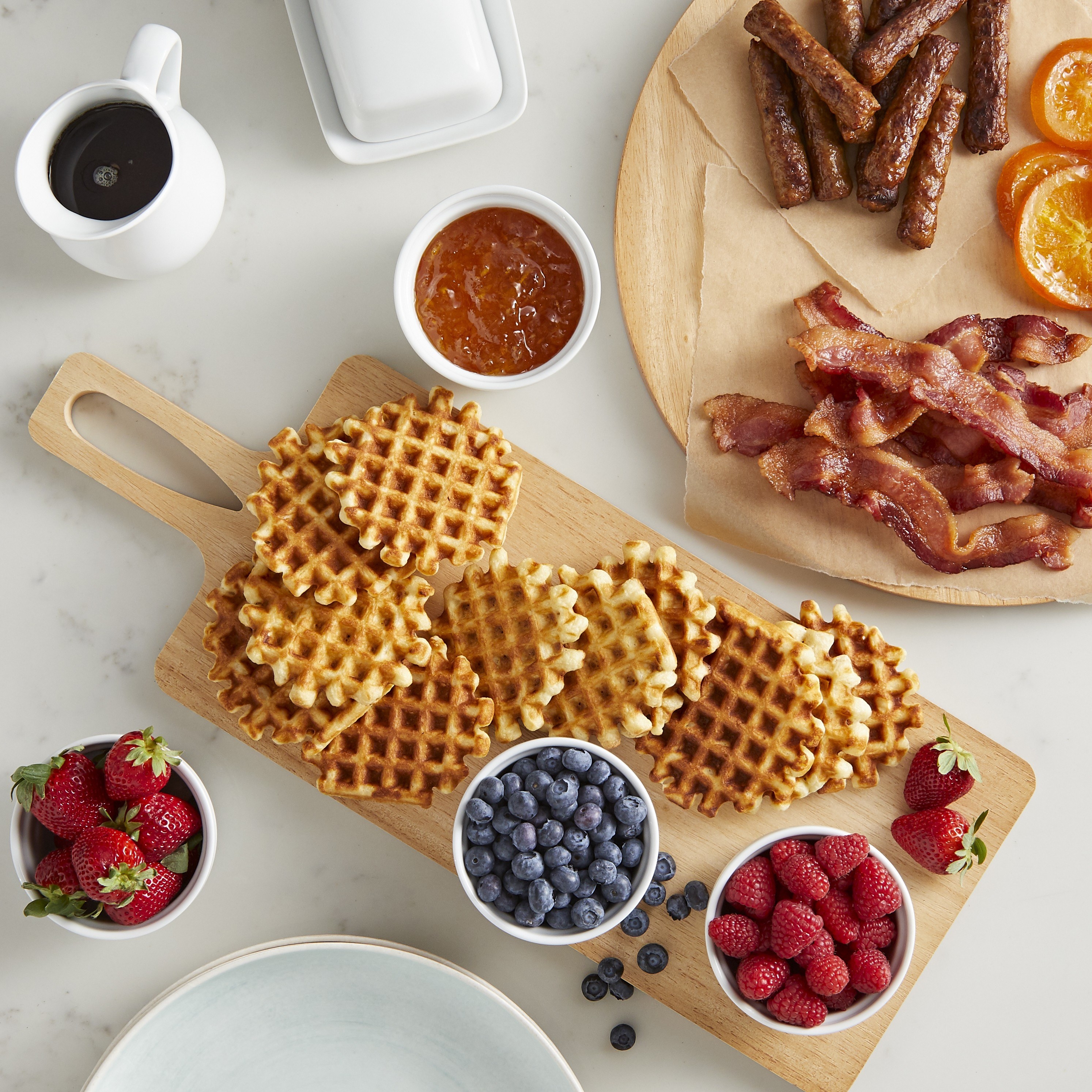 the square board with waffles and fruit on it
