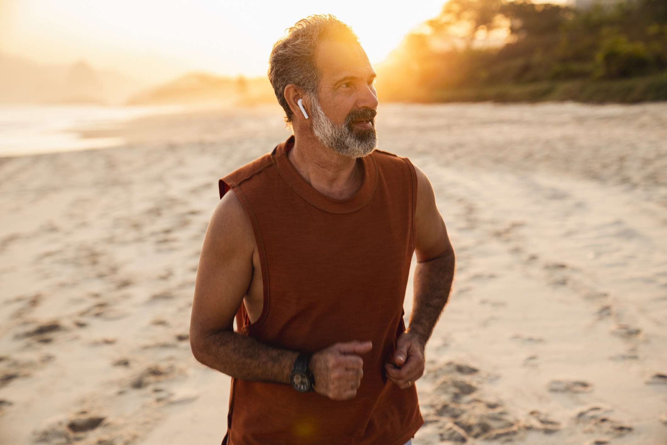 A man runs on the beach in the morning with wireless headphones