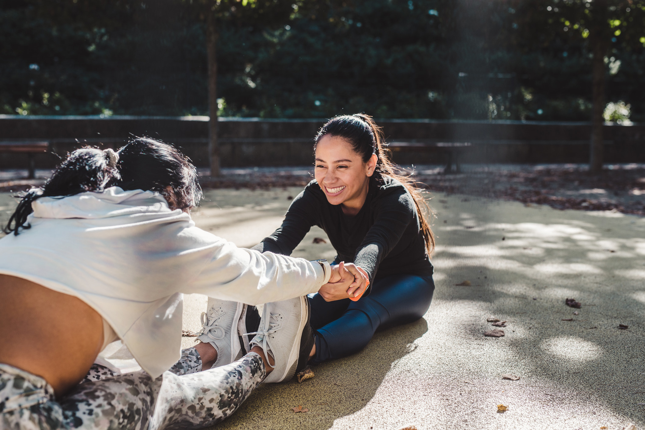 Two friends in fitness gear help each other stretch