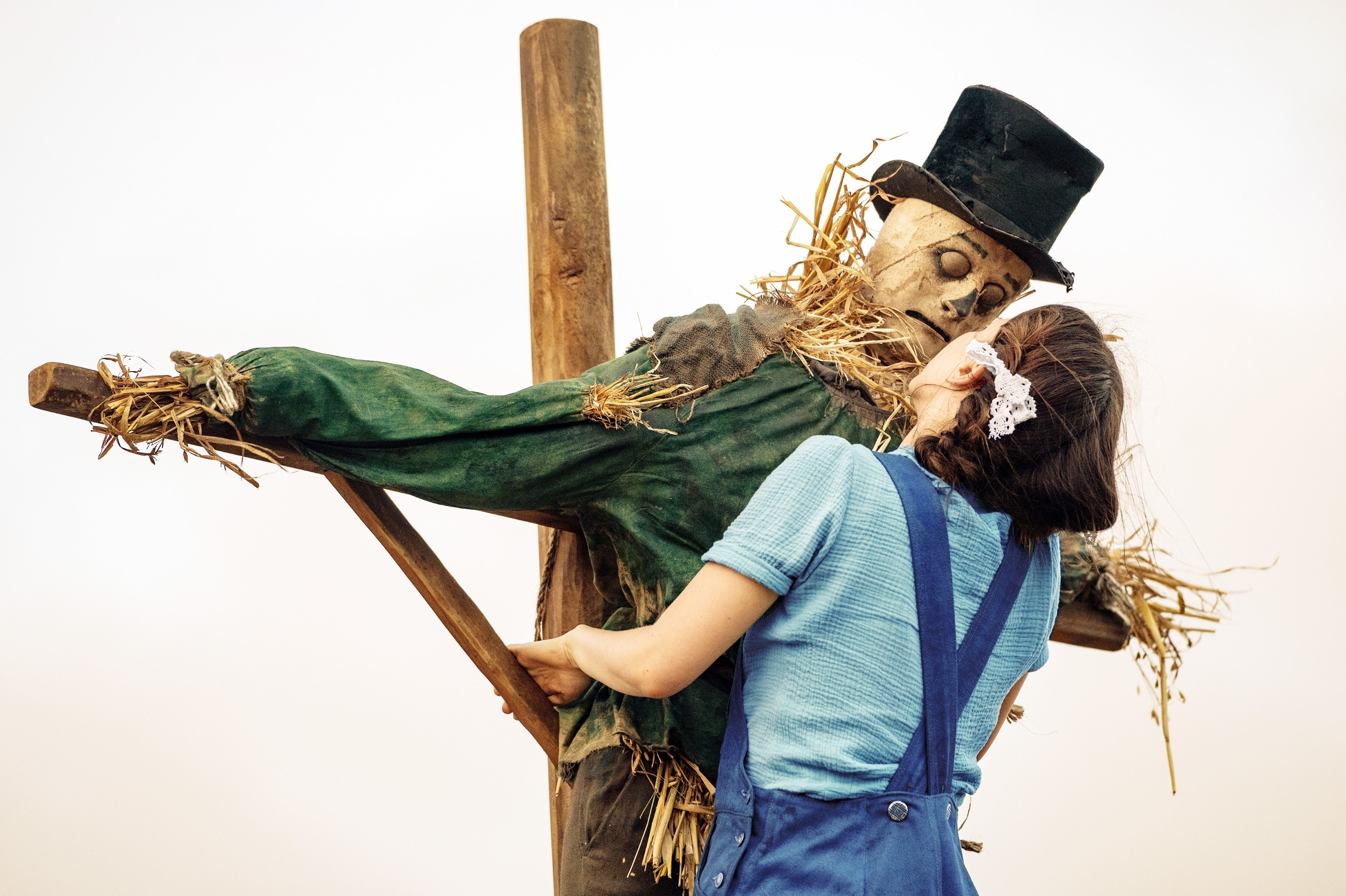 A woman kisses a scarecrow