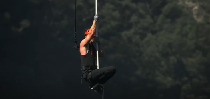 Chris Hemsworth climbing a rope suspended from a helicopter