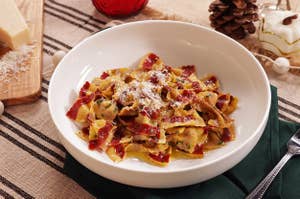 A bowl of bow tie red candy-striped pasta with parmesan on top, set upon a holiday-inspired table setting 